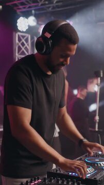 Dj operating equipment in dark club scene. Suitable for music events, nightlife promotions, and entertainment industry designs. Vibrant and energetic.