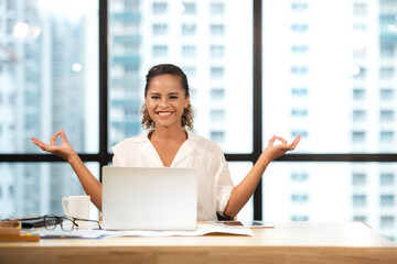 Relax time. Successful smiling business woman relaxing and meditating after working in modern office, mindful peaceful and practicing breathing yoga exercises and resting healthy care.