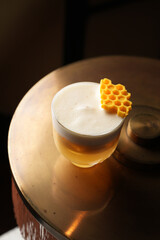 Honey cocktail with foam and honeycomb garnish on a table