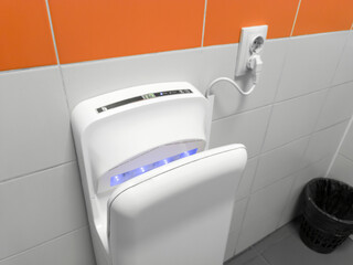 Air hand dryer on the wall of a public restroom WC