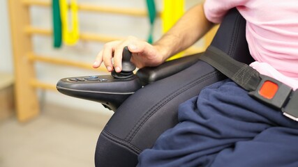 Person operating power wheelchair joystick for increased mobility © Iván Moreno