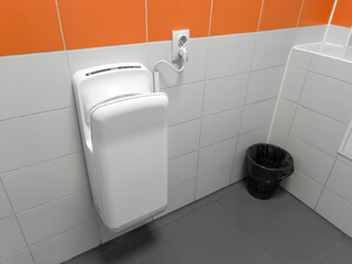 Air hand dryer on the wall of a public restroom WC