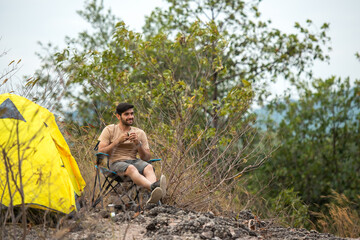 Lifestyle man travel hiker adventure and tent camping on mountain nature landscape. Young people tourist backpack drinking coffee in tent after activity outdoor for destination leisure