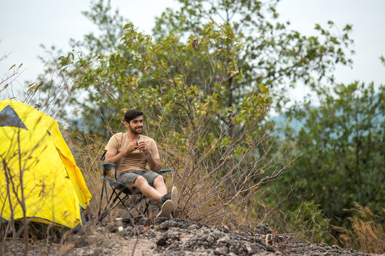 Lifestyle man travel hiker adventure and tent camping on mountain nature landscape. Young people tourist backpack drinking coffee in tent after activity outdoor for destination leisure