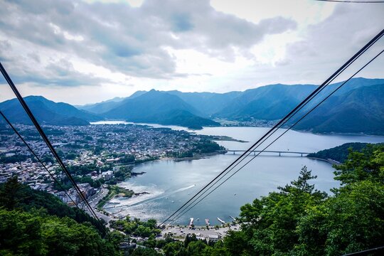 This breathtaking landscape offers a panoramic view of a lakeside town nestled among rolling hills and mountains. The aerial perspective reveals the harmony between the natural surroundings and the ur