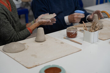 Seniors learning pottery craft in busy workshop