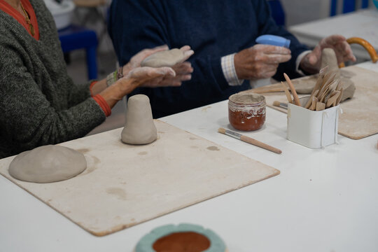 Seniors learning pottery craft in busy workshop - Powered by Adobe