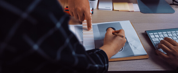 Creative collaboration unfolds in a modern office setting as hands engage in sketching, exploring color palettes, and discussing ideas for a design project. SACTR