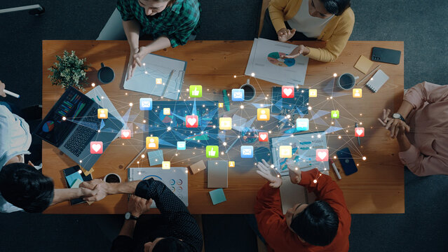 A diverse group of professionals collaborates on a digital marketing strategy, utilizing data analysis and social media graphics on a modern workspace table. Trope