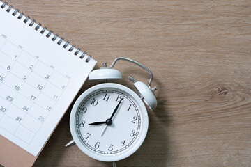 close up of calendar and alarm clock on the wooden table background, planning for business meeting or travel planning concept