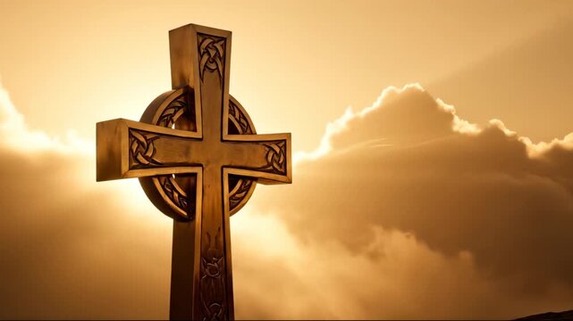 Celtic cross stands against golden sunset sky with clouds. Stone cross shows carved celtic pattern at sunrise. Golden light illuminates cross monument. Sunset reveals celtic cross with dramatic sky.