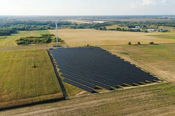 Windmill and photovoltaic panels in green landscape