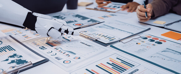 A modern office scene showcasing collaboration between humans and robots, featuring detailed data analysis, charts, and innovative teamwork strategies for productivity.Noogenesis
