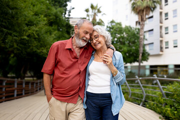 Senior couple embracing, smiling, enjoying happy outdoor walk