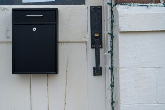 Black Mailbox and Handle on a White Wooden Door - Powered by Adobe