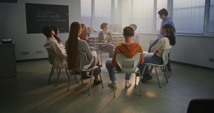 Teen Students Sit in Circle With Caring Teacher Discussing Psychology and Self Awareness. Concept Student Wellbeing, Mindfulness, and Importance of Emotional Support in Modern Schools. Slow Motion.