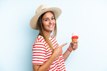 Young caucasian woman holding an ice cream isolated on blue background and pointing it