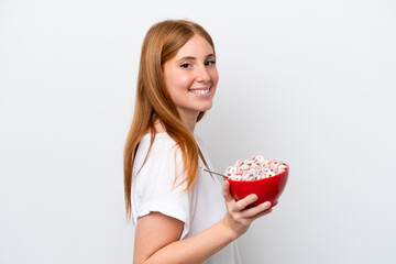 Young redhead woman holding a bowl of cereals isolated on white background smiling a lot