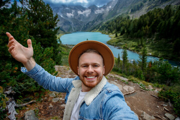 Portrait hipster Young caucasian male enjoying mountain lake view while smiling in nature, travel hike blog