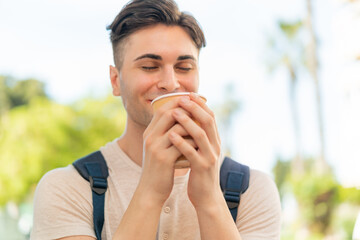 Young handsome man holding a take away coffee