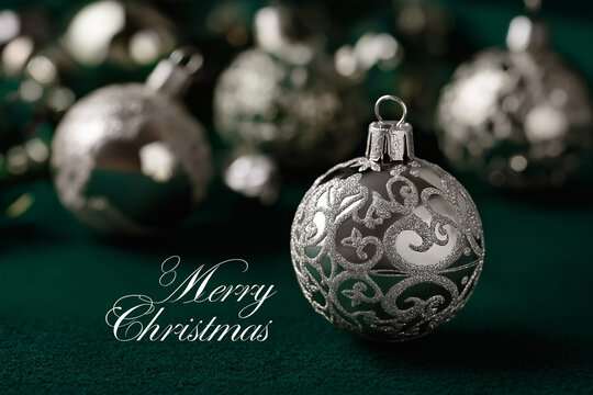 Elegant silver Christmas ornaments shimmer against a rich green background, with &ldquo;Merry Christmas&rdquo; in matching silver font creating a luxurious festive mood.