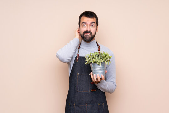 Man holding a plant over isolated background having doubts - Powered by Adobe