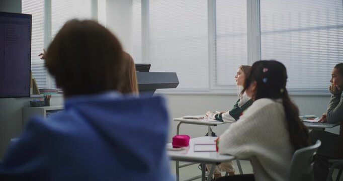 Confident Female Instructor Teaches Coding to Attentive Students, Pointing Lines Code on Interactive Display. Concept Digital Education, IT Learning Environment, and Classroom Technology. Dolly Shot.