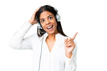Telemarketer African American woman working with a headset over isolated chroma key background surprised and pointing finger to the side