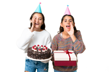 Friends girls holding gift and a birthday cake over isolated chroma key background shouting and announcing something