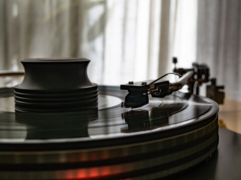 Close-up of spinning vinyl record on turntable, capturing motion of grooves and stylus. Classic analog music setup evokes nostalgia, creativity and warm sound	