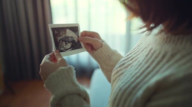 Tender moment of an expecting mother holding an ultrasound photo, capturing the early joy of pregnancy and the emotional connection to her growing baby in a warm, cozy home atmosphere.