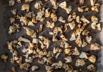 Pieces of baked cauliflower in baking tray on wooden table. Top view