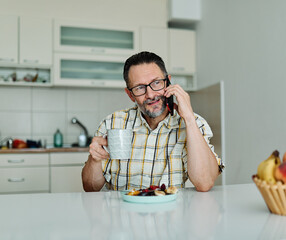 Man enjoying breakfast while using smartphone in modern kitchen during morning hours
