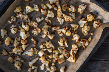 Pieces of baked cauliflower in baking tray on wooden table. Top view