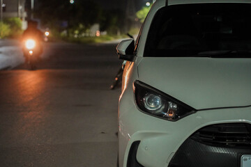 Naklejka premium White Car and Motorcycle Headlights on a Dark Urban Street at Night