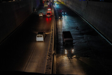 Night Traffic in a Dimly Lit Underpass with Reflective Road