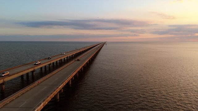 Slow-motion drone footage tracking along the east side of the Causeway Bridge over Lake Pontchartrain, filmed in soft golden-hour light with expansive water views.