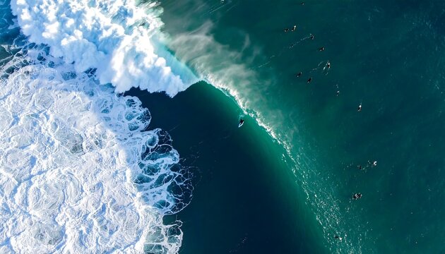 Thrilling aerial view of surfers riding massive ocean waves with dynamic white foam crashing spectacularly against the deep blue sea