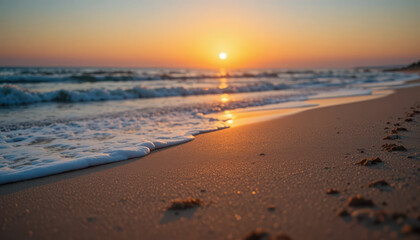 Fototapeta premium Sunset over the ocean waves washing onto the beach