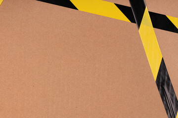 Black and yellow striped сaution tape on cardboard background. prohibitory warning tape packaging...