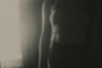 Silhouette of a person standing, illuminated by soft sunlight creating a mysterious and introspective atmosphere