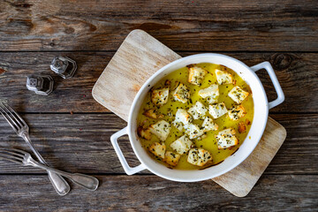 Baked feta cheese in baking dish on wooden table. Top view	