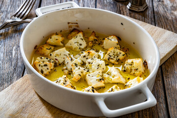 Baked feta cheese in baking dish on wooden table	