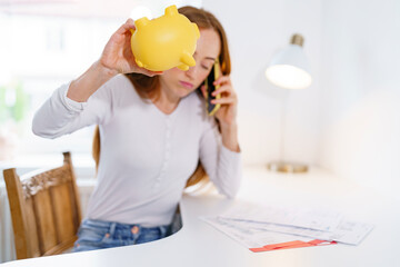 Young woman managing finances while on a phone call at home office