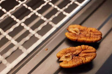 Close-up of a half pecan kernel on a metal grill mesh, natural texture and lighting, food photography