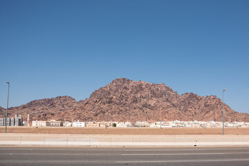Rocky barren mountain with white low rise houses of a small town at its base