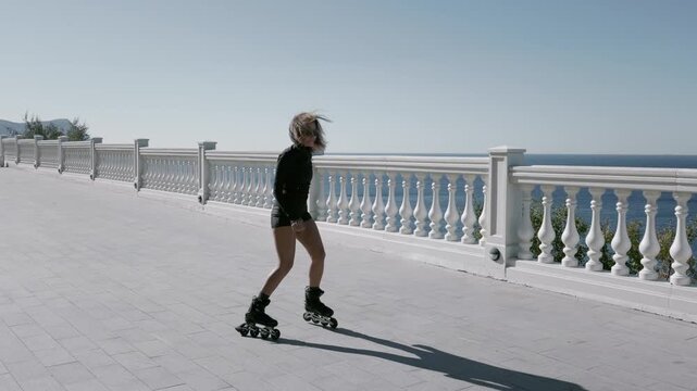 Woman rollerblading on the embankment on a sunny day, active sport.