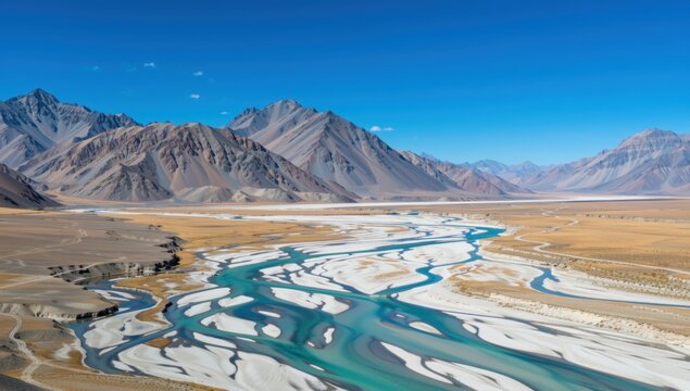 Aerial view of a river flowing through a mountainous landscape under a clear blue sky - Powered by Adobe
