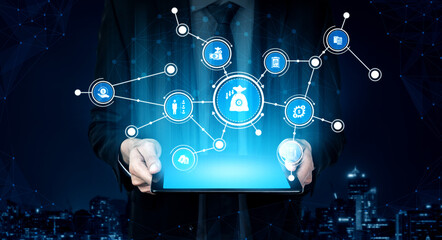 A businessman holds a tablet displaying various digital icons, representing online services and networking concepts, set against a modern night cityscape. Tessel