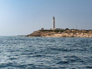 Iconic lighthouse rising above the coast, shot from offshore.